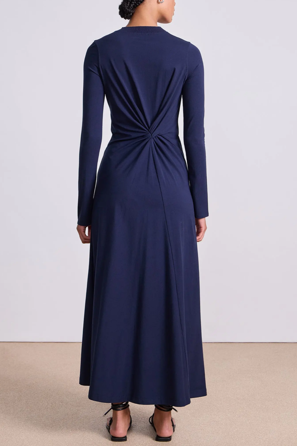Navy blue long-sleeve dress with a knot detail at the back on a plain background