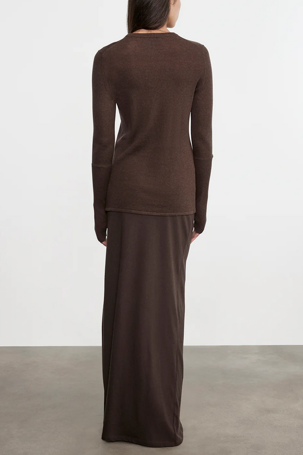 Person wearing a brown long-sleeve top and long skirt set against a white background