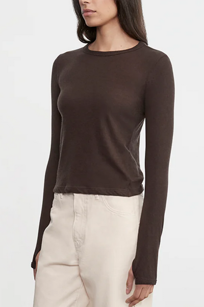 Woman wearing a brown long-sleeve top and beige pants on a white background