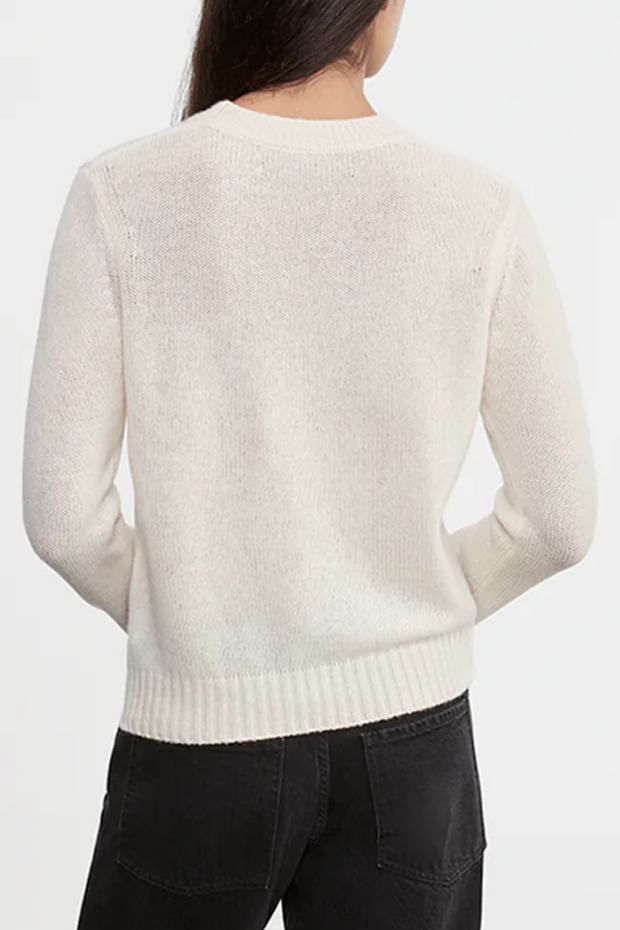 Person wearing a cream sweater on a white background