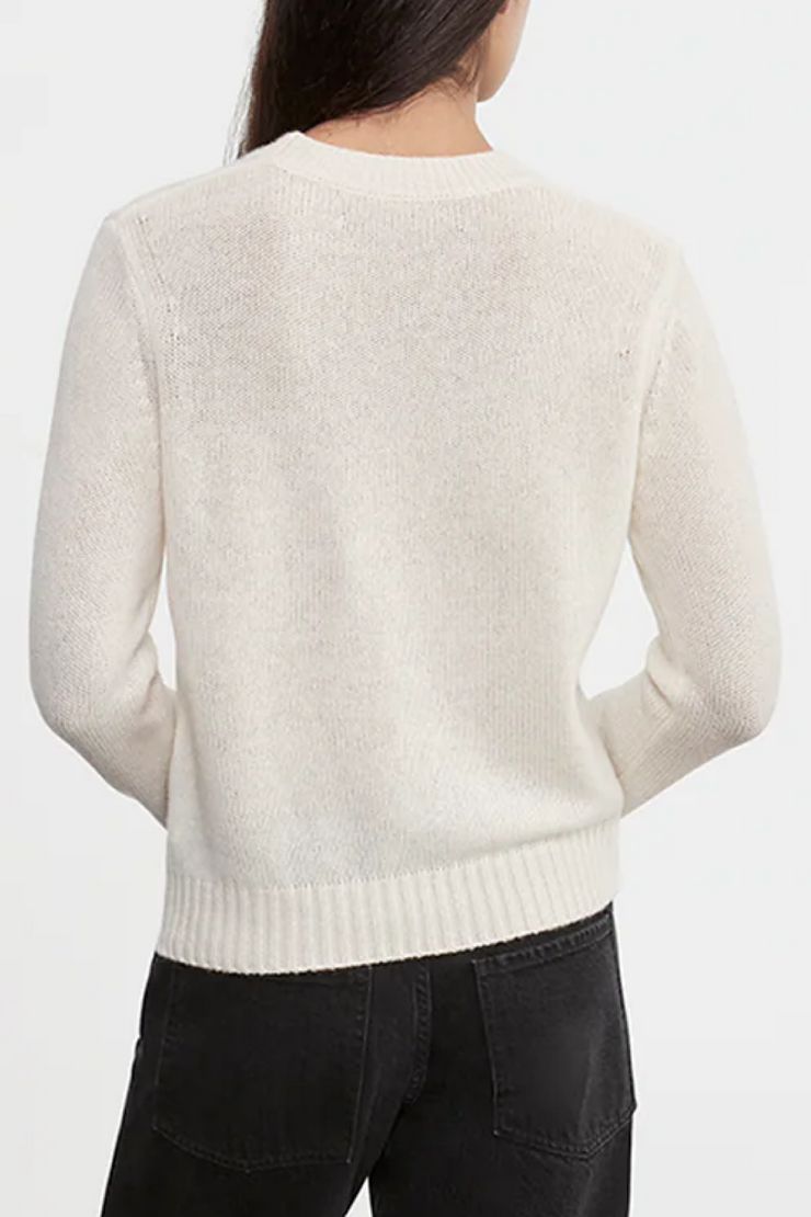 Person wearing a cream sweater on a white background