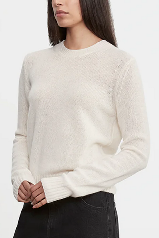 Woman wearing a white sweater on a plain background