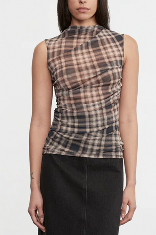 Woman wearing a plaid sleeveless top with a plain background