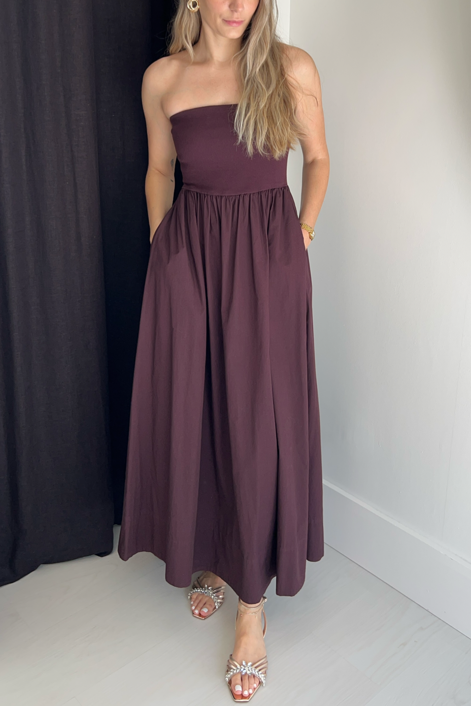 Woman wearing a strapless dark cherry dress against a plain background