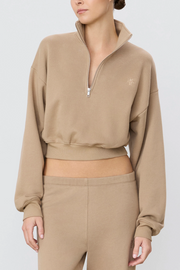 Person wearing taupe cropped zip up and pants on a light gray background