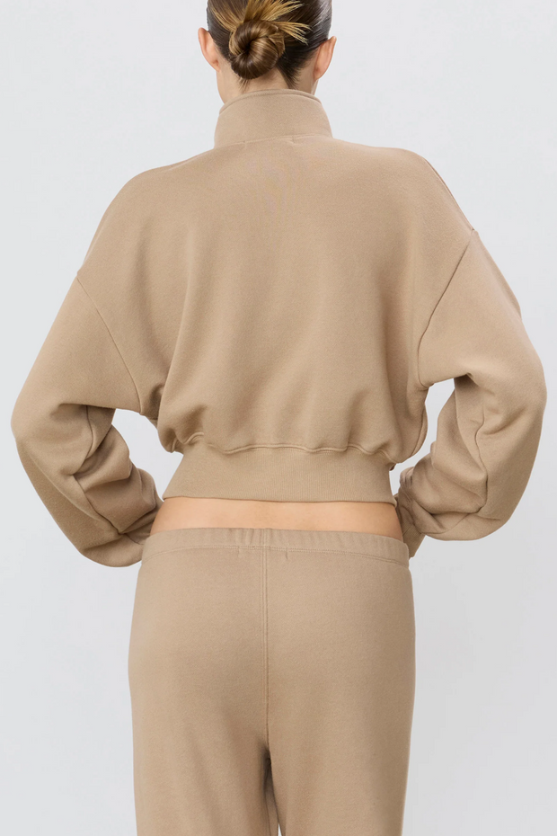 Person wearing a taupe sweatshirt and pants on a white background