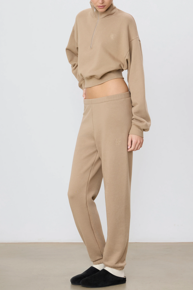 Person wearing a taupe sweatshirt and pants on a white background