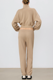 Person wearing a taupe sweatshirt and pants set on a white background