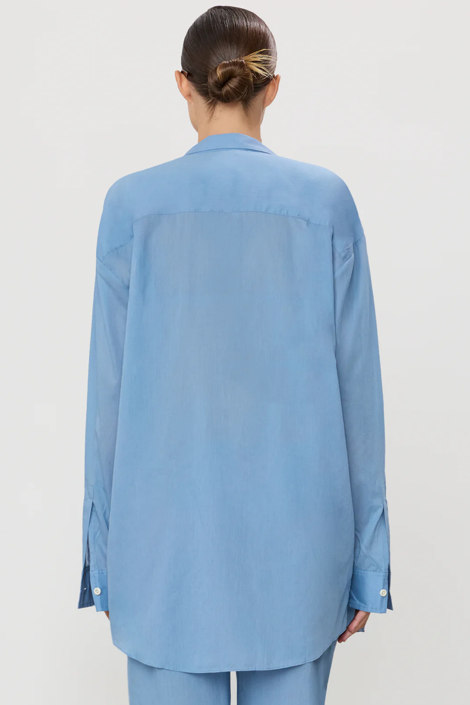 Person wearing a light blue shirt and pants on a plain background