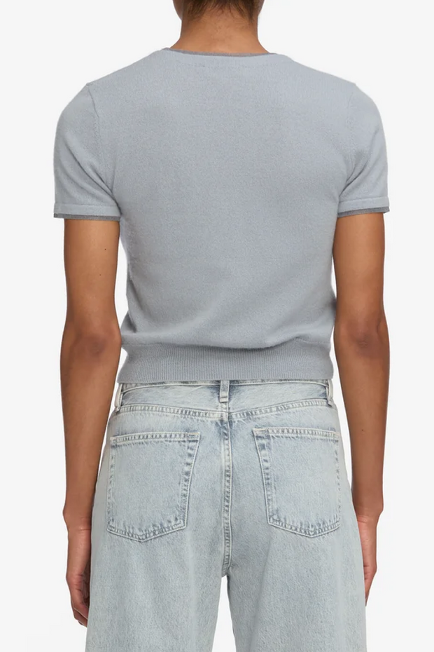 Person wearing a light gray t-shirt and light blue jeans on a white background