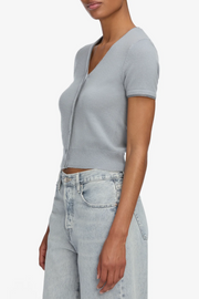 Person wearing a gray short-sleeve cardigan and light blue jeans on a white background