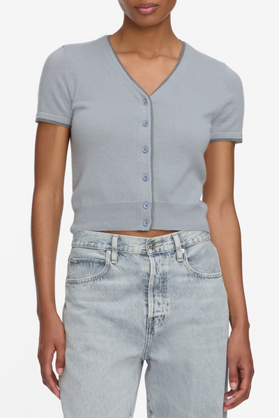 Person wearing a light blue cardigan and jeans on a white background