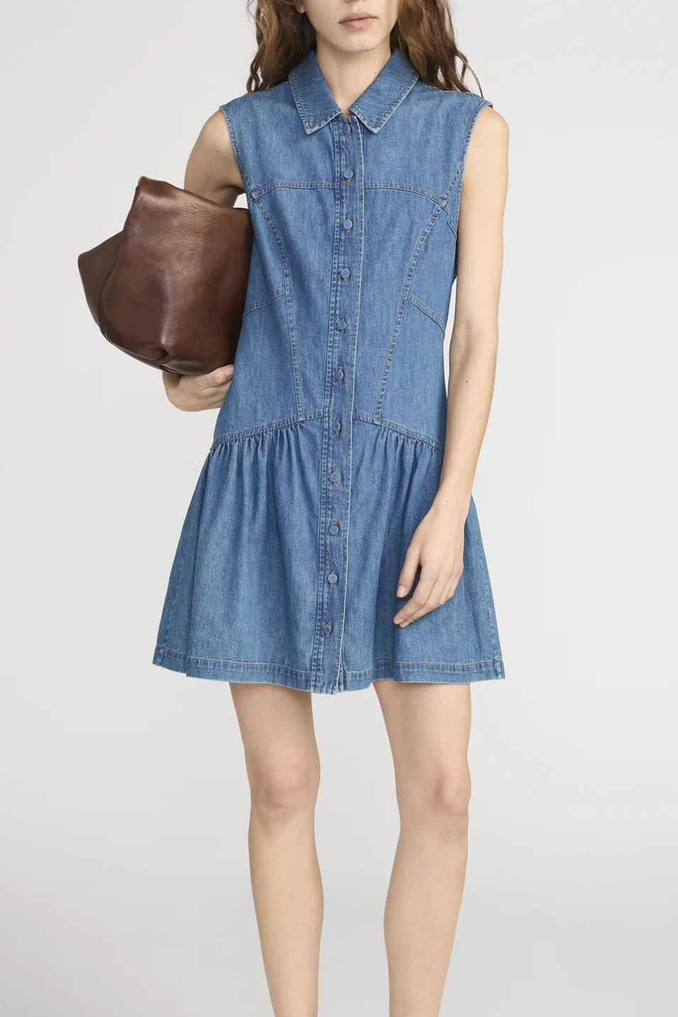 women wearing a relaxed fit denim dress with a brown tote 
