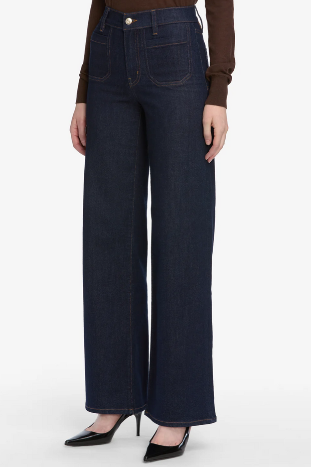 Person wearing dark blue wide-leg jeans on a white background