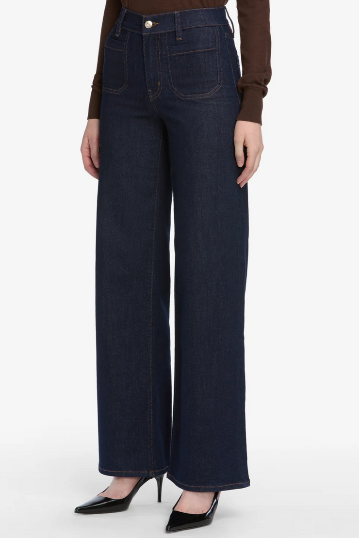 Person wearing dark blue wide-leg jeans on a white background