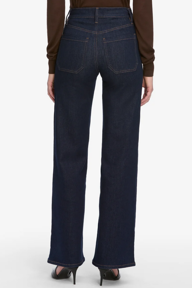 Dark blue jeans worn by a person on a white background