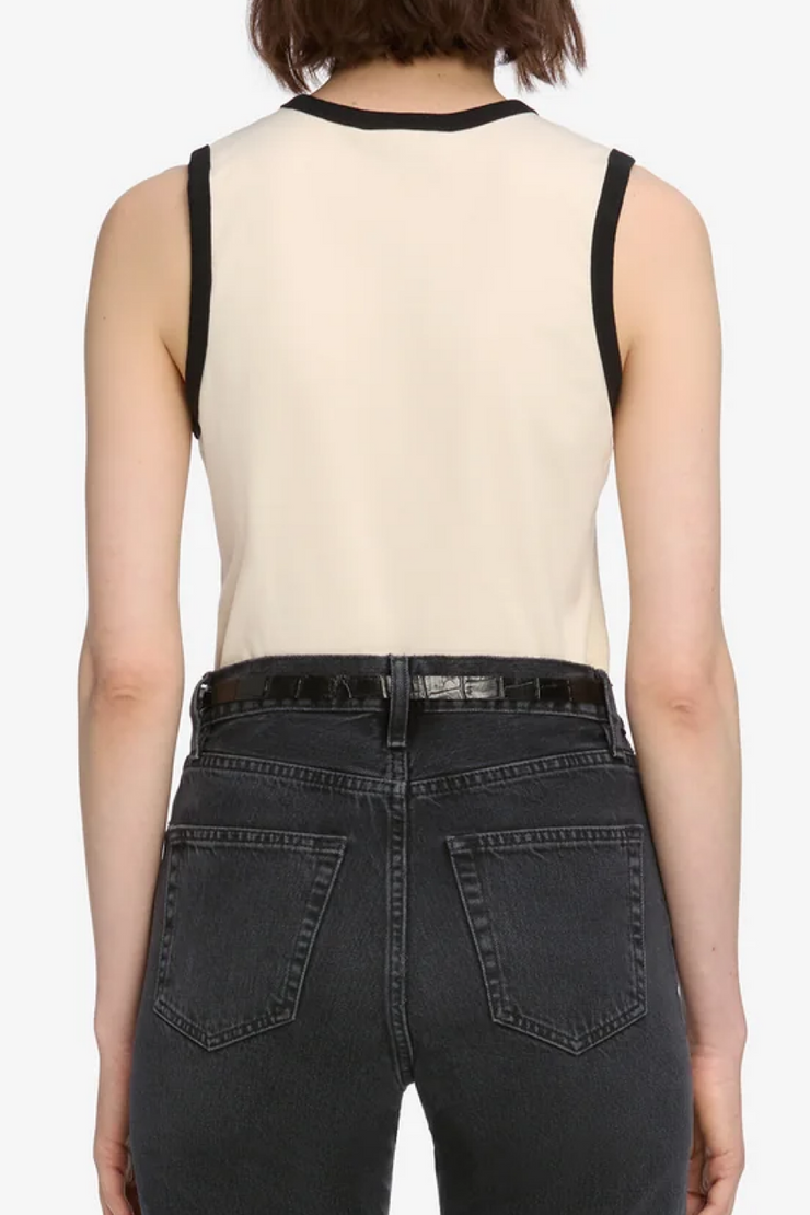 Person wearing a cream tank top and black jeans on a white background