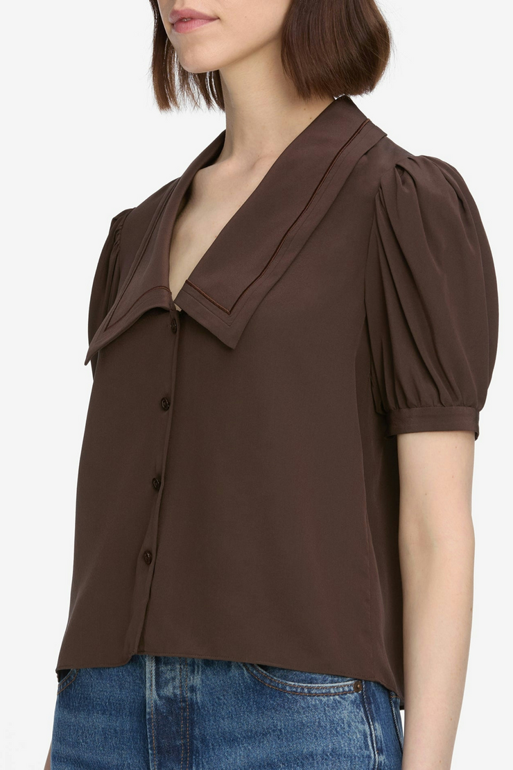 Brown blouse with short sleeves and a collar worn by a person on a white background