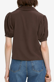 Brown blouse with puff sleeves worn by a person on a white background