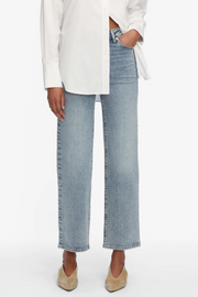 Person wearing light blue jeans and a white shirt on a white background