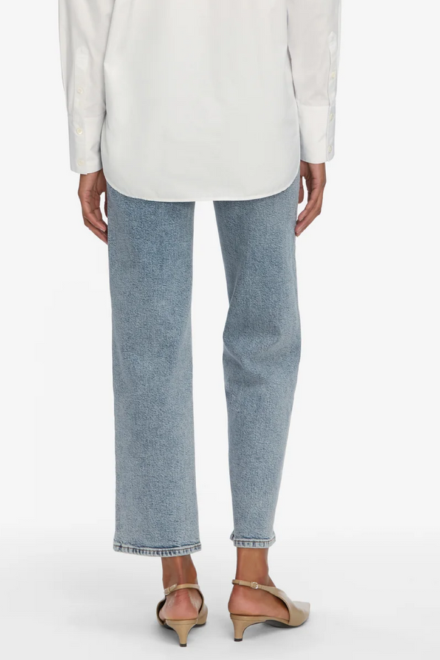 Person wearing light blue jeans and a white top on a white background
