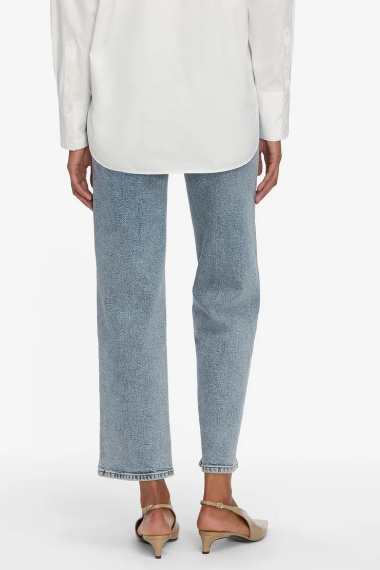 Person wearing light blue jeans and a white top on a white background