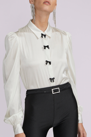 Image of model wearing Generation Love Arly blouse in white with black bows and buttons