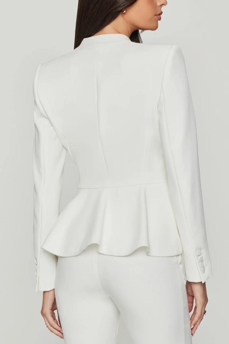 White peplum jacket worn by a person on a plain background
