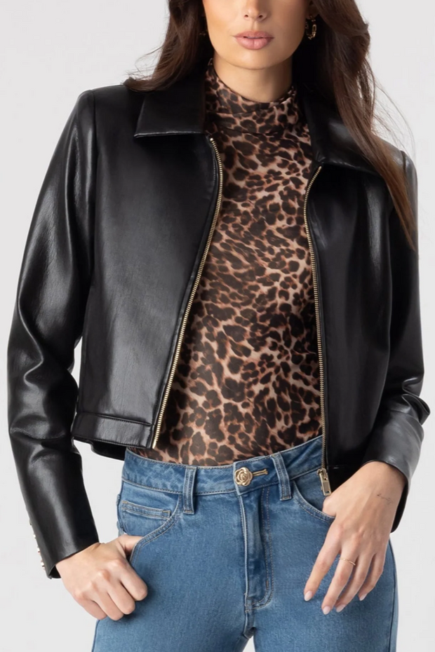 Person wearing a black leather jacket, leopard print top, and blue jeans on a white background