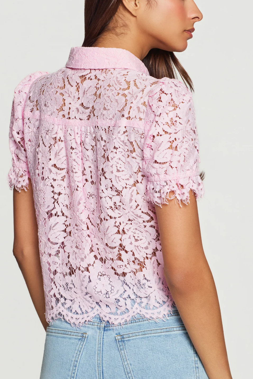 Pink lace blouse worn by a person on a white background