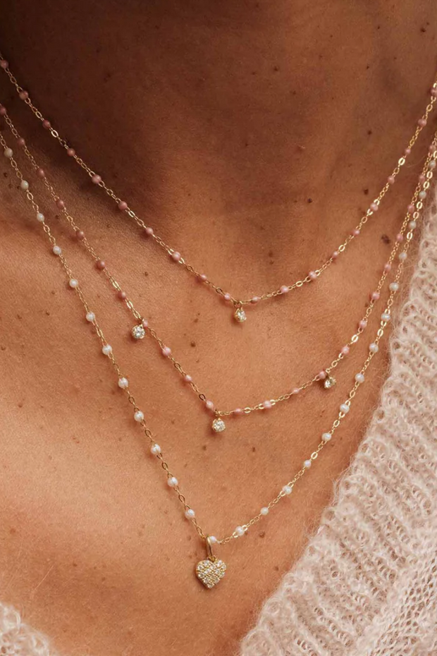 Close-up of a person wearing multiple necklaces with heart pendants.