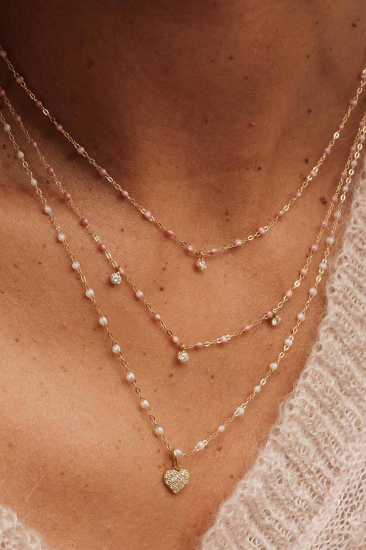 Close-up of a person wearing multiple necklaces with heart pendants.