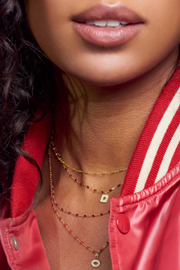 Close-up of a person wearing layered necklaces with a red jacket