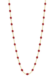 Necklace with cherry beads on a gold chain against a white background