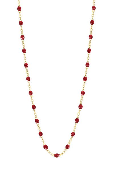 Necklace with cherry beads on a gold chain against a white background