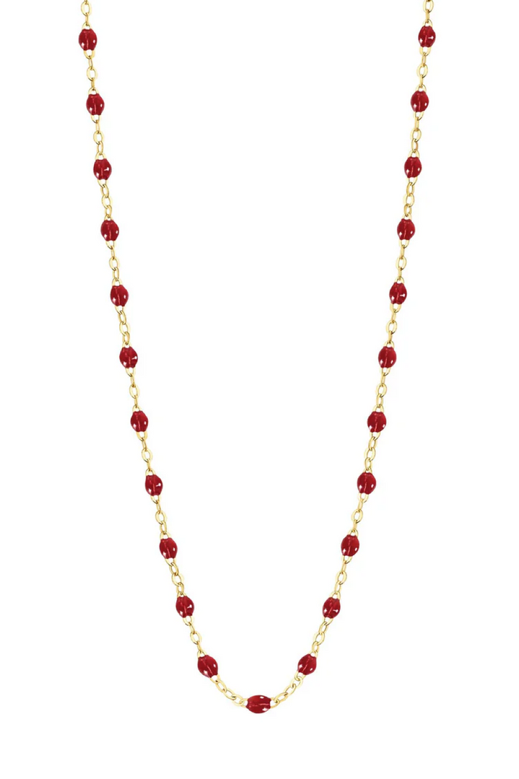 Necklace with cherry beads on a gold chain against a white background