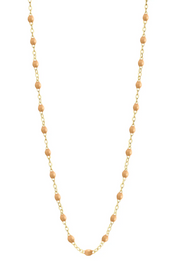 Necklace with nude beads on a gold chain against a white background