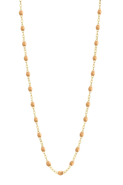 Necklace with nude beads on a gold chain against a white background