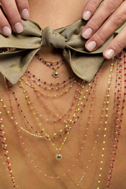 Close-up of a person wearing multiple beaded necklaces with a bow detail.