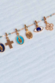 Bracelet with various charms including crosses and eye designs on a light blue background