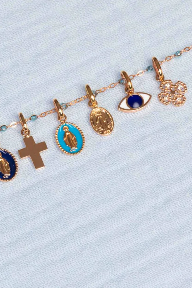 Bracelet with various charms including crosses and eye designs on a light blue background