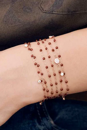 Multiple beaded bracelets on a wrist against a dark background