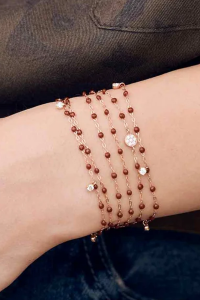 Multiple beaded bracelets on a wrist against a dark background