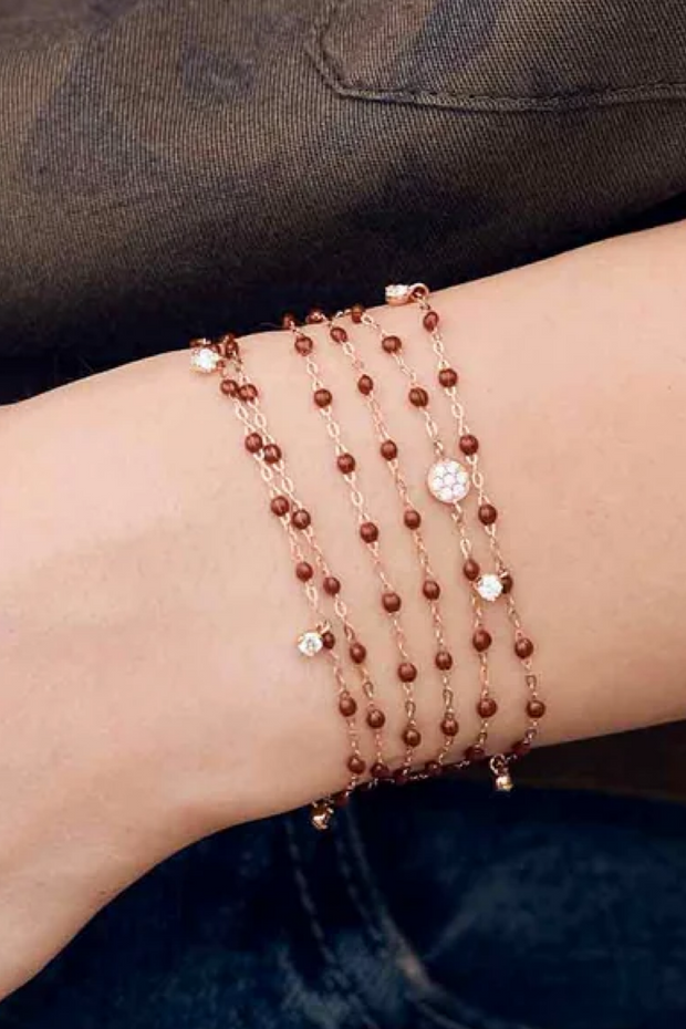 Multiple beaded bracelets on a wrist against a dark background