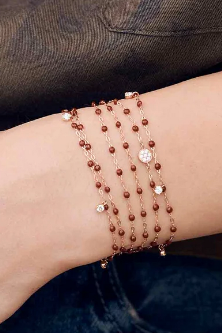 Multiple beaded bracelets on a wrist against a dark background