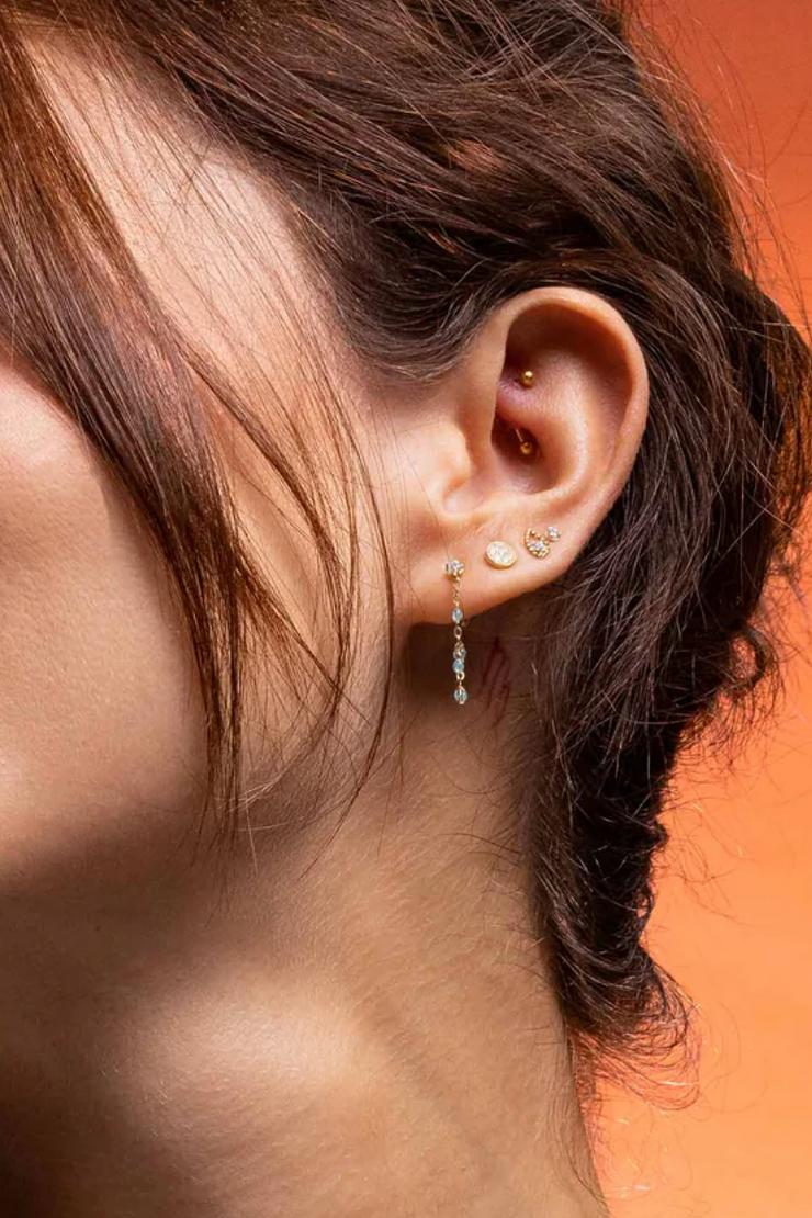 Close-up of an ear with earrings against an orange background