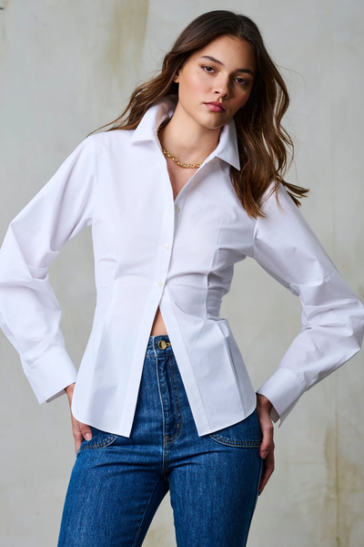 Woman wearing a white shirt and blue jeans against a neutral background