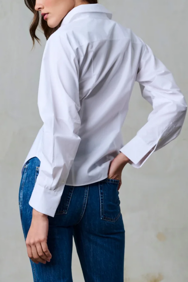 Person wearing a white shirt and blue jeans against a plain background