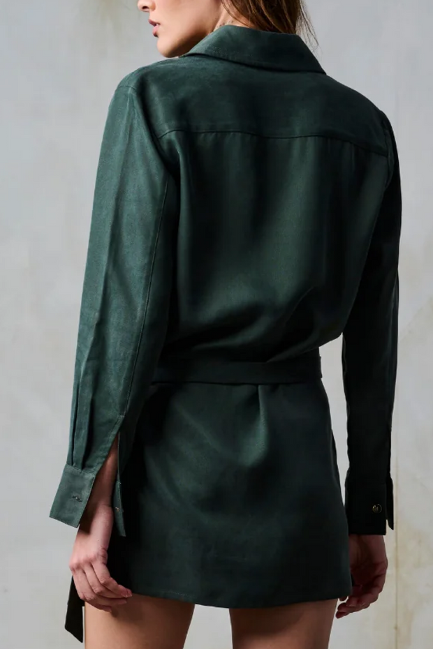 Person wearing a green shirt and skirt set against a plain background