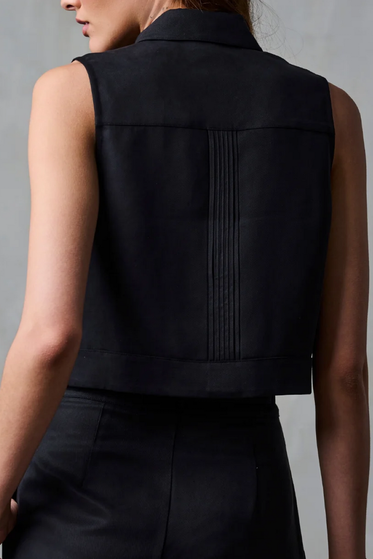 Black sleeveless top worn by a person against a gray background